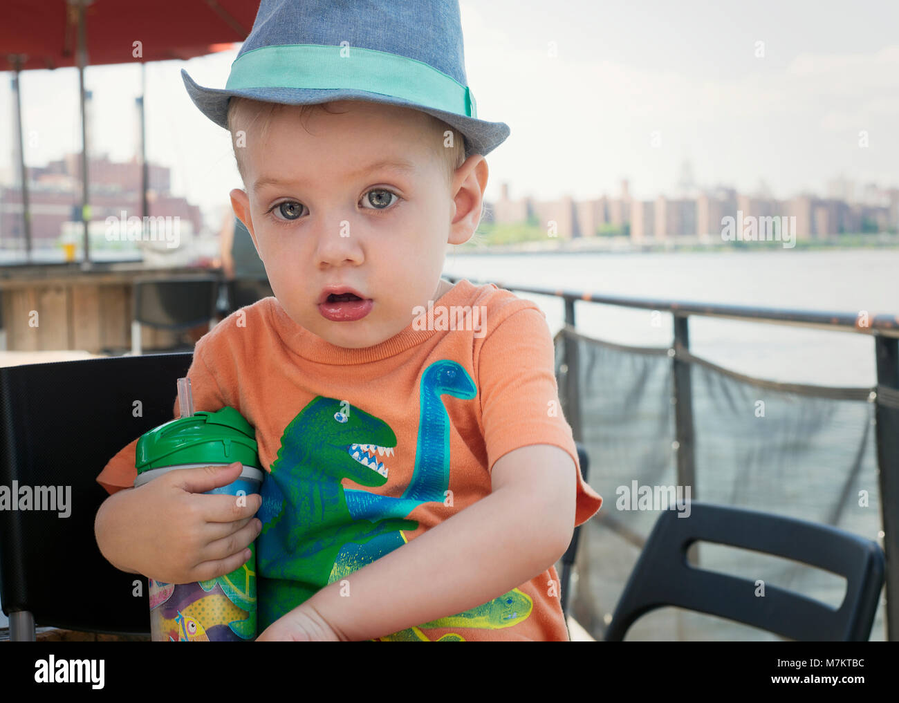 A baby hanging out at an outdoor restaurant wearing a dinosaur shirt. Stock Photo