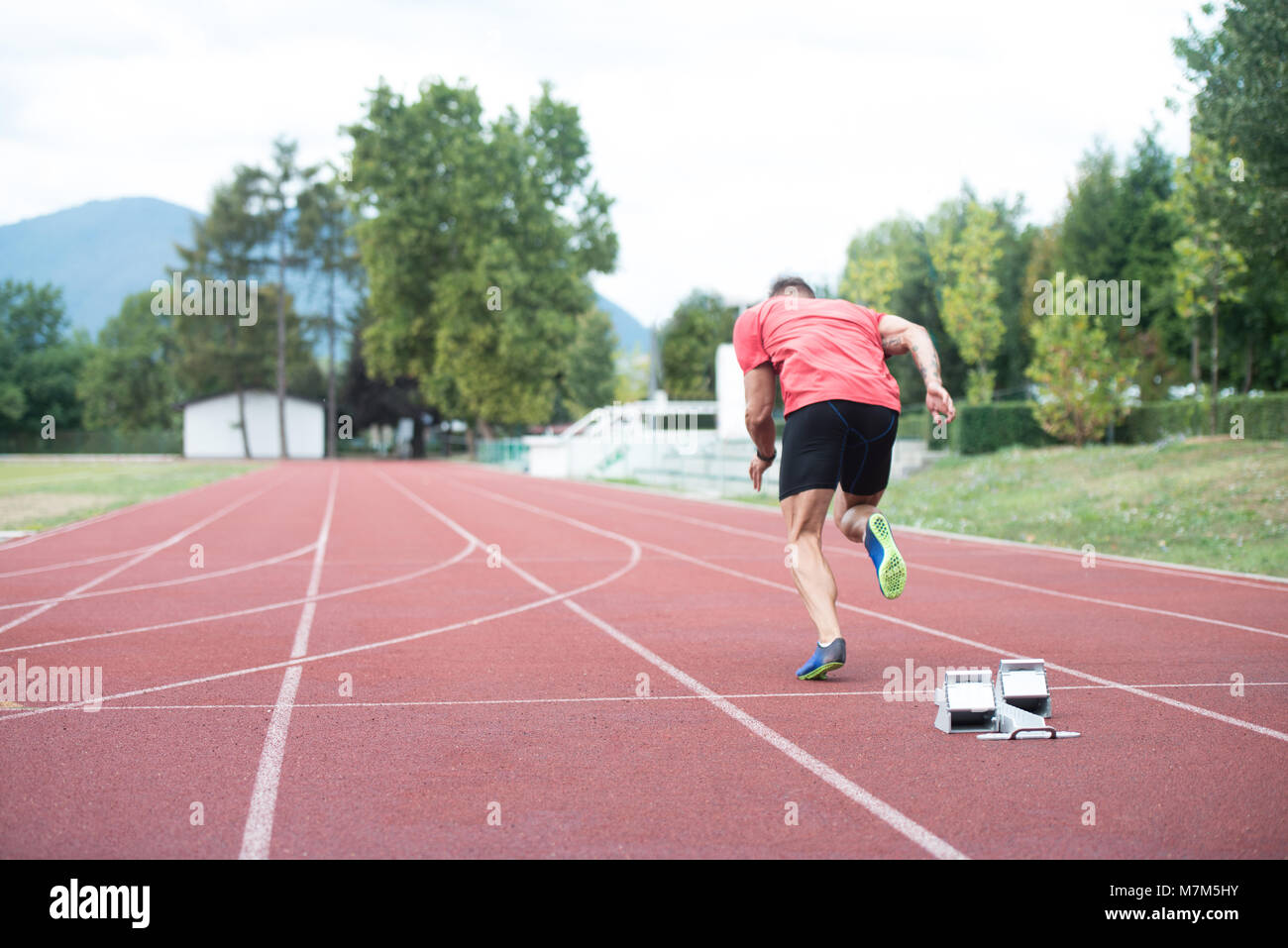 Sprinter Man Running on Red Tracks Lanes in Track and Field Stadium in