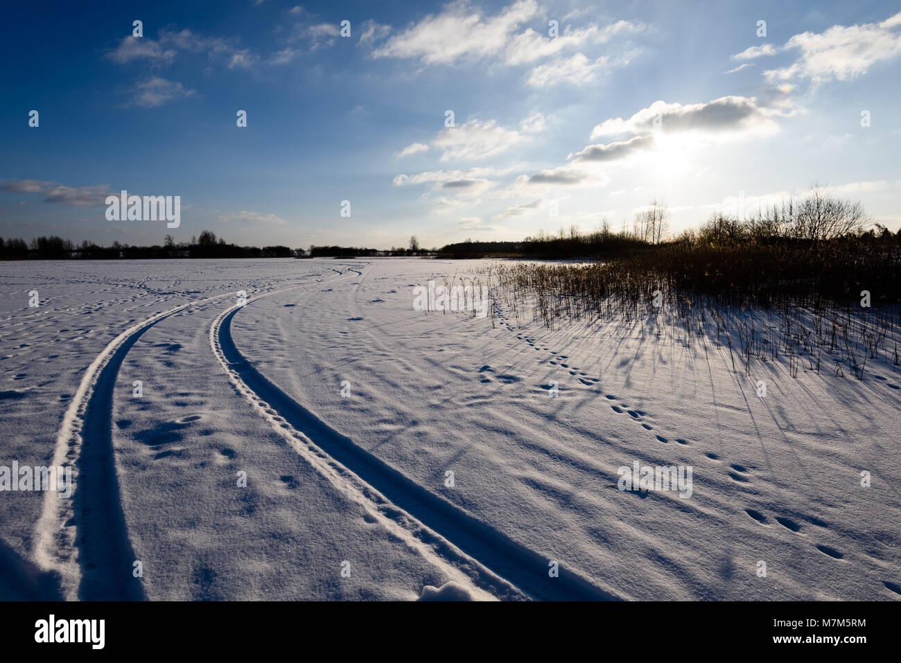 snowy winter road covered in deep snow with car tire tracks going in ...