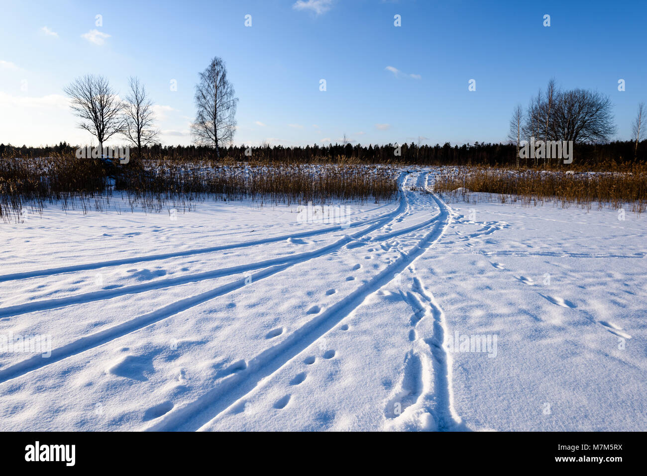 snowy winter road covered in deep snow with car tire tracks going in ...