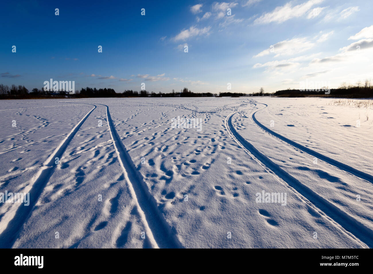 snowy winter road covered in deep snow with car tire tracks going in ...
