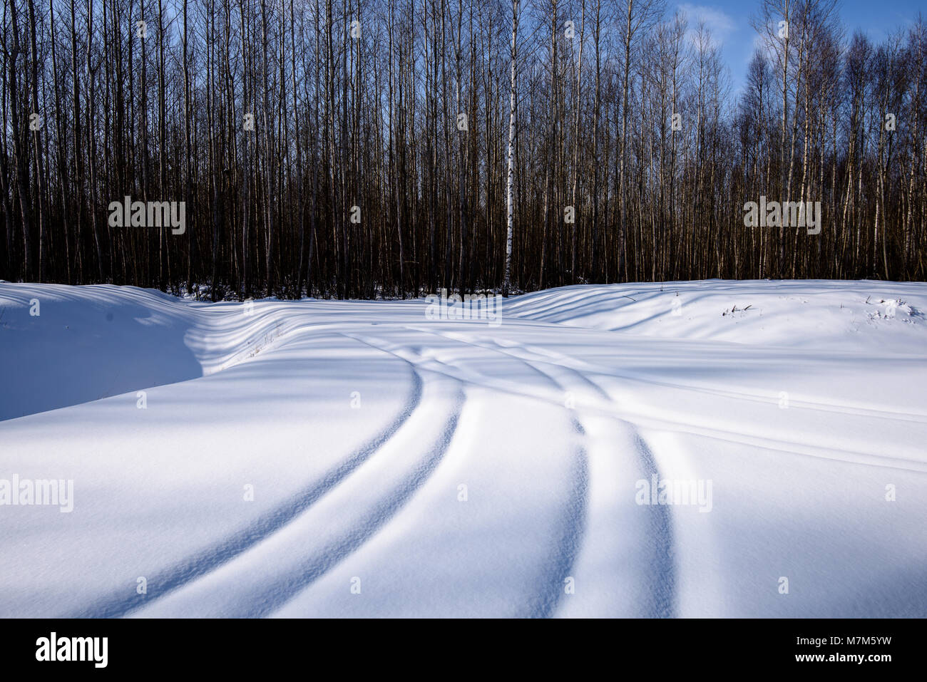 snowy winter road covered in deep snow with car tire tracks going in ...