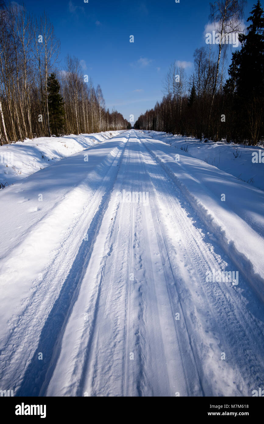 snowy winter road covered in deep snow with car tire tracks going in ...