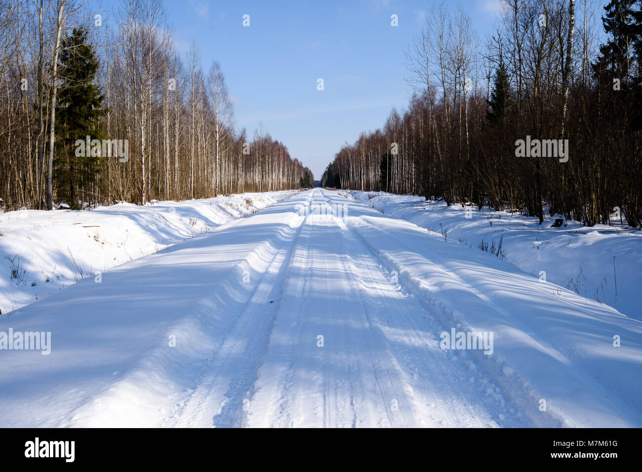snowy winter road covered in deep snow with car tire tracks going in ...