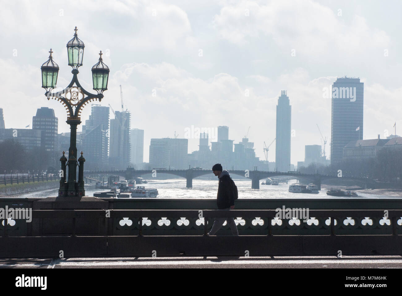 A pedestrian crosses the River Thames on a cold and misty morning Stock Photo