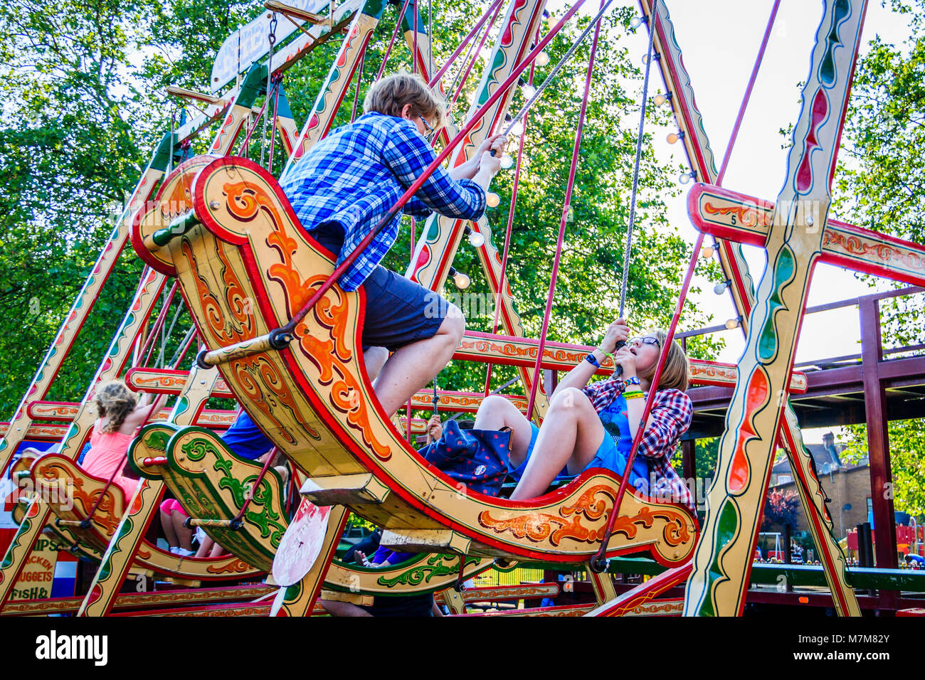 Mother and daughter enjoying the swing chairs at Carter's traditional steam fair in Priory Park, North London, UK Stock Photo