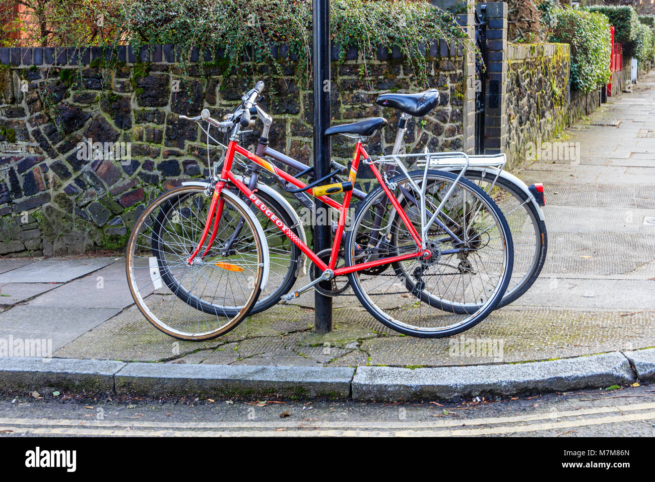 Two abandoned bicycles chained to a street sign in a residential street in North London, UK Stock Photo