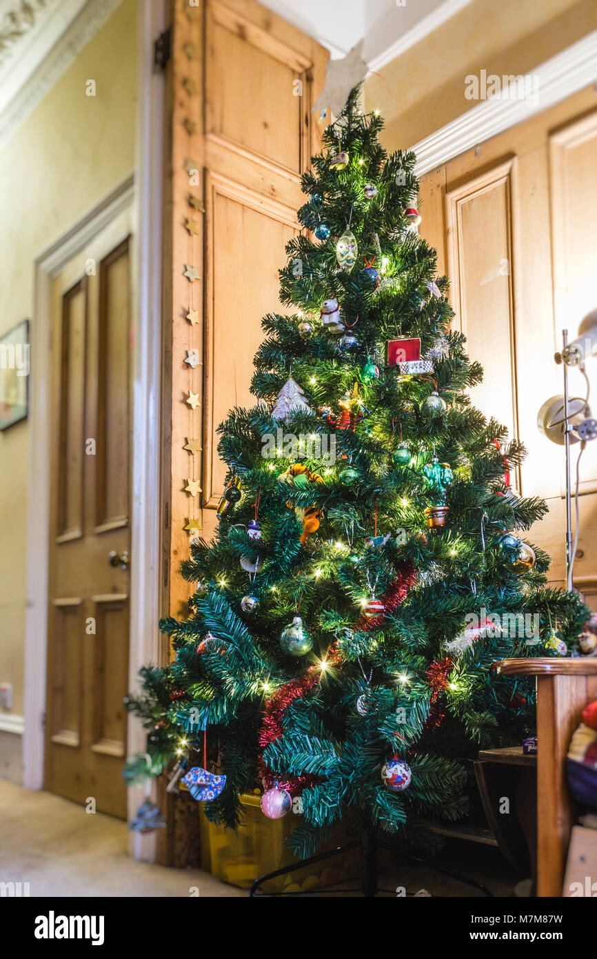 Christmas tree decorated with lights and baubles in the living room of a British family home Stock Photo