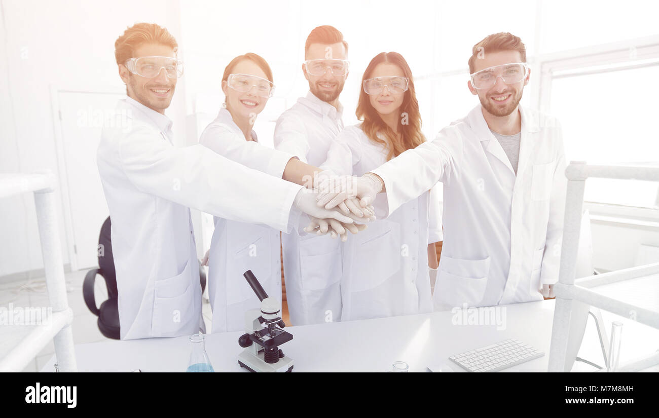 successful team of young scientists with hands clasped together Stock ...