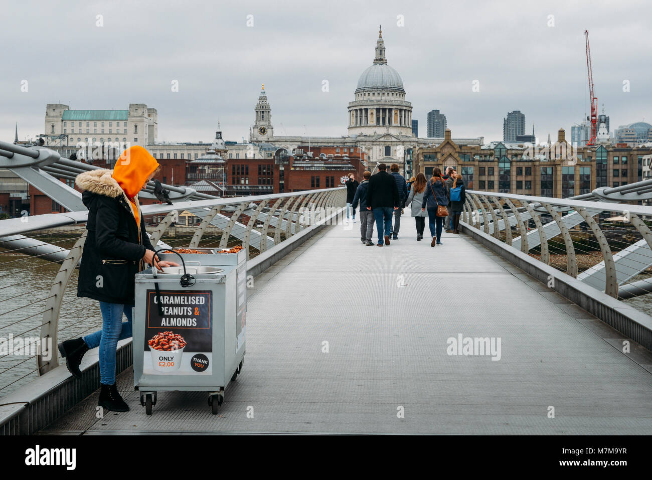 London, UK - March 10, 2018: Young Cameralised peanut female seller at London's Millennium Bridge overlooking St. Paul's Cathedral Stock Photo