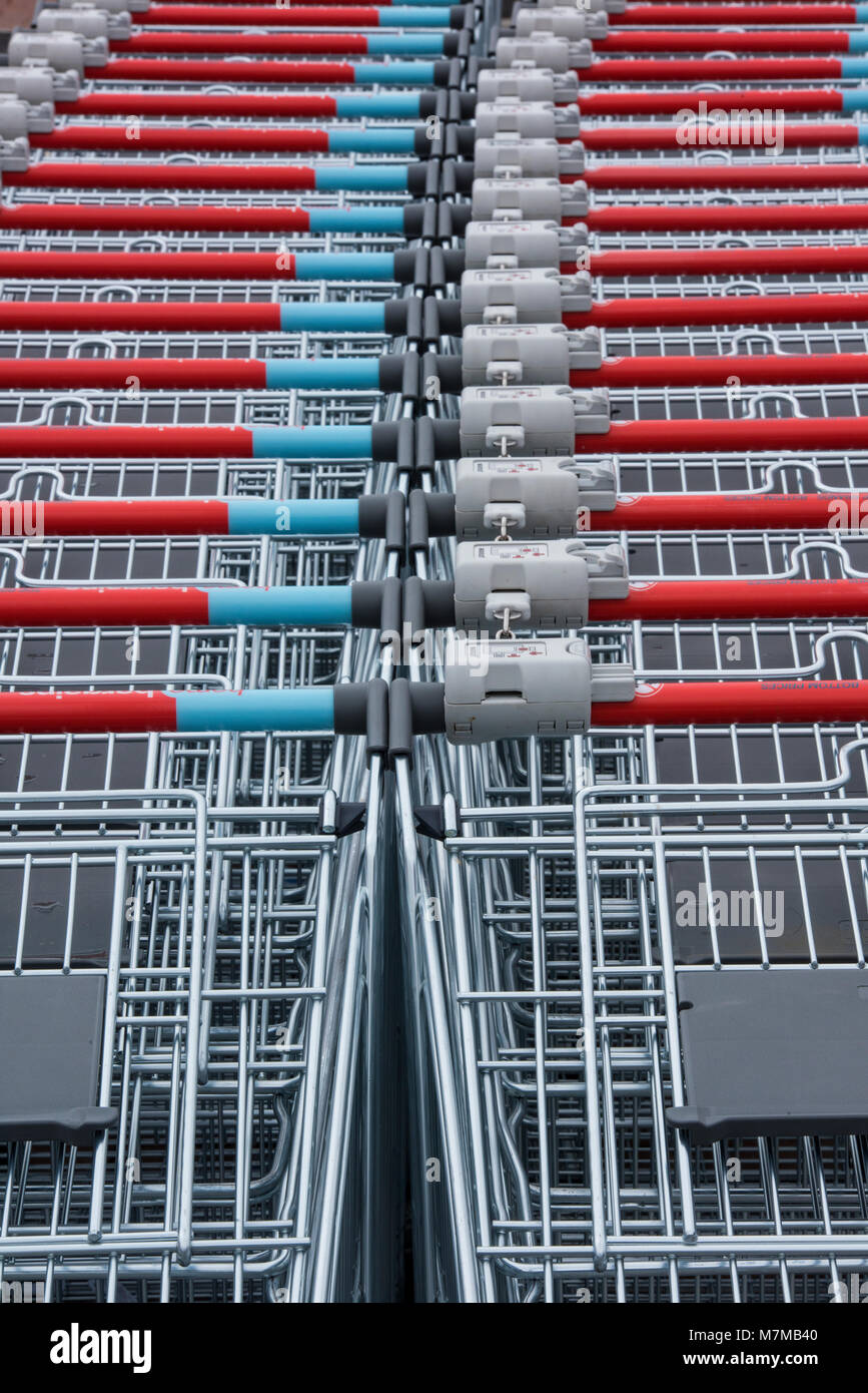 rows of shopping trolleys making forming a pattern in straight lines and uniform shapes. Retailers on high street supermarkets and hypermarkets carry. Stock Photo