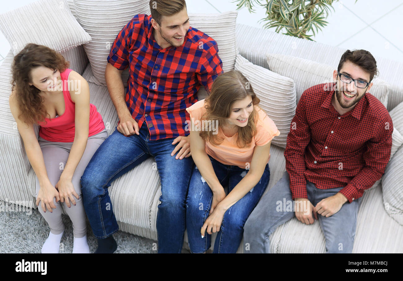 triumphant group of friends laughing while sitting on the couch in the ...