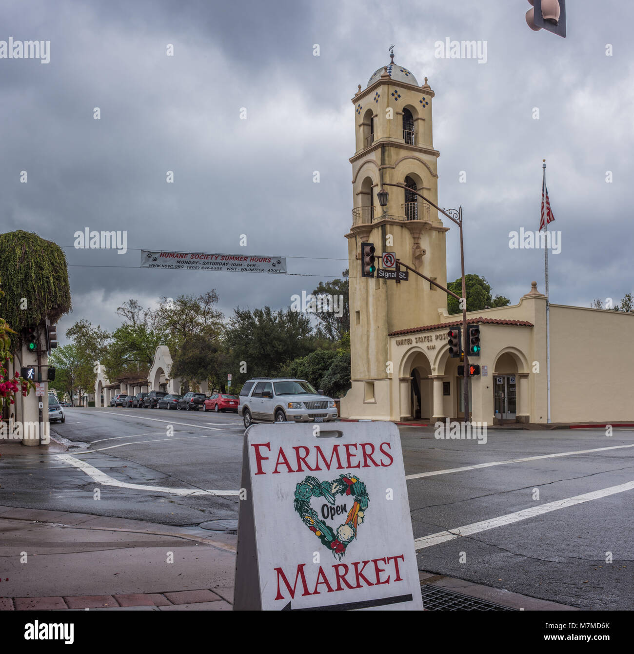 Downtown Ojai tower closet to rain clouds as street sign points way to weekend farmers market.  Shot on March 11 in Ojai, California, United States. Stock Photo