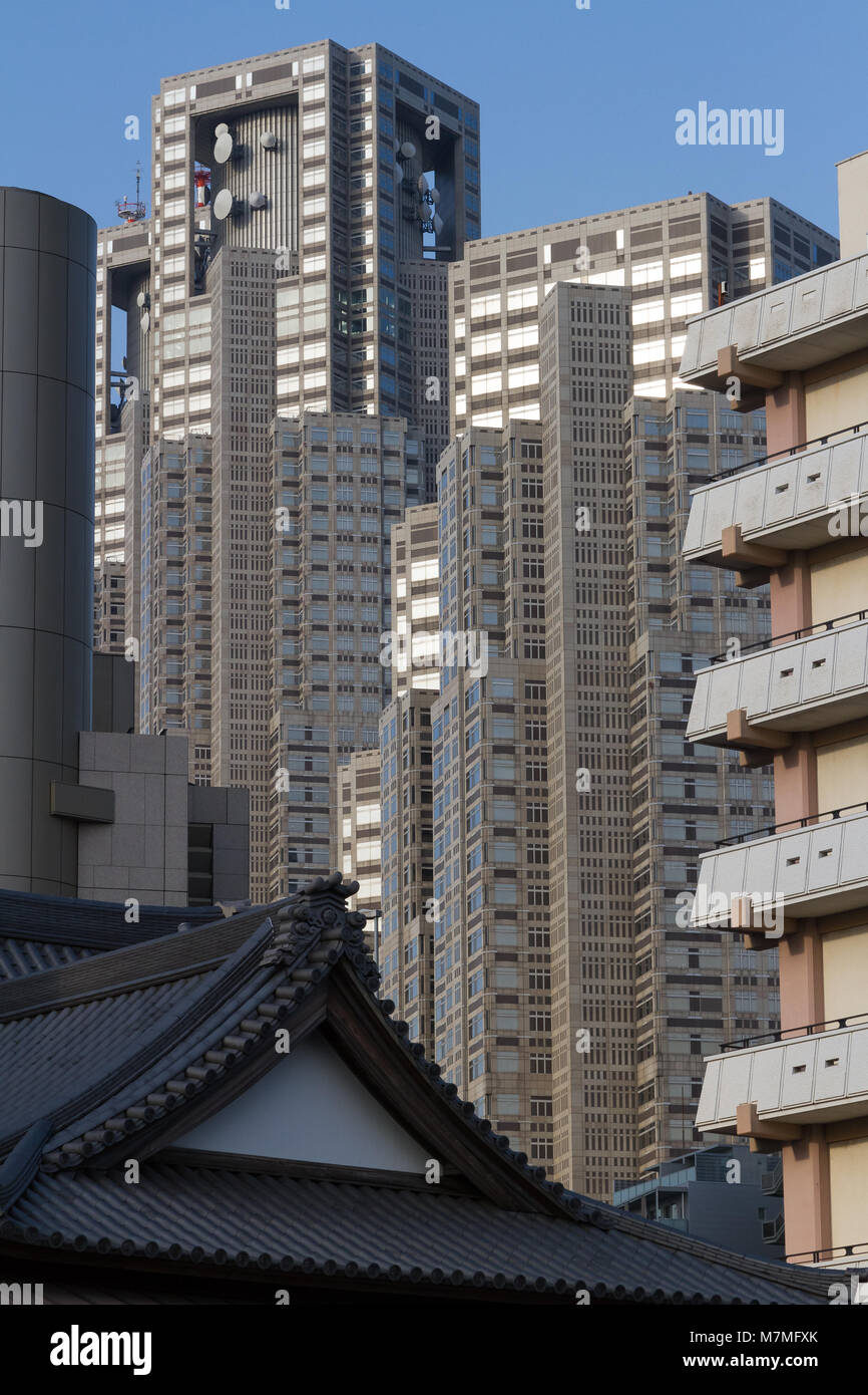 Tokyo Metropolitan Government Towers behind apartment buildings and a shrine roof in Shinjuku, Tokyo, Japan. T Stock Photo