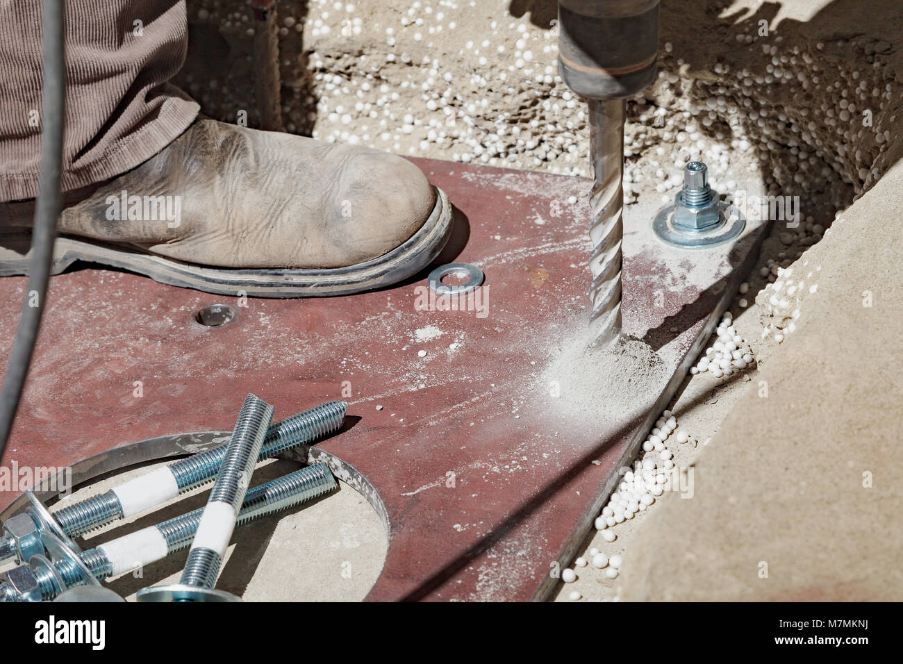 The builder uses an electric drill to make a hole in the concrete to ...