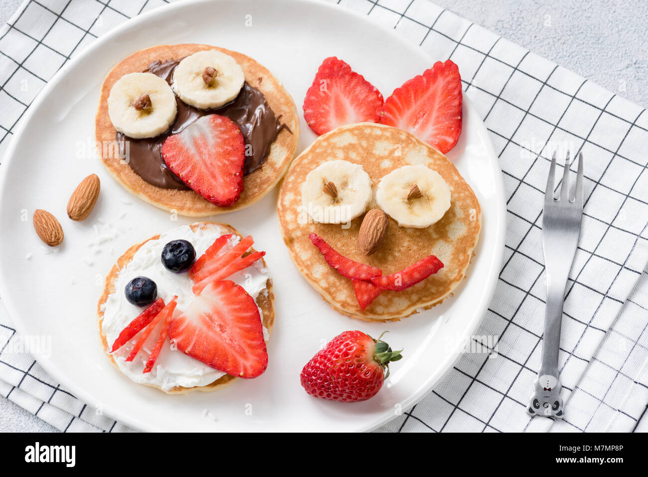Colorful breakfast meal for kids. Pancake food art, funny animal faces made with fruits, nuts and chocolate spread. Concept of kids meal, kids breakfa Stock Photo