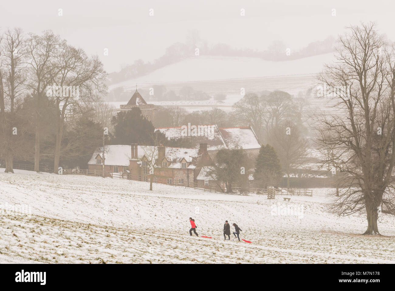 Three people sledging and enjoying the snow in the Chilterns Stock Photo