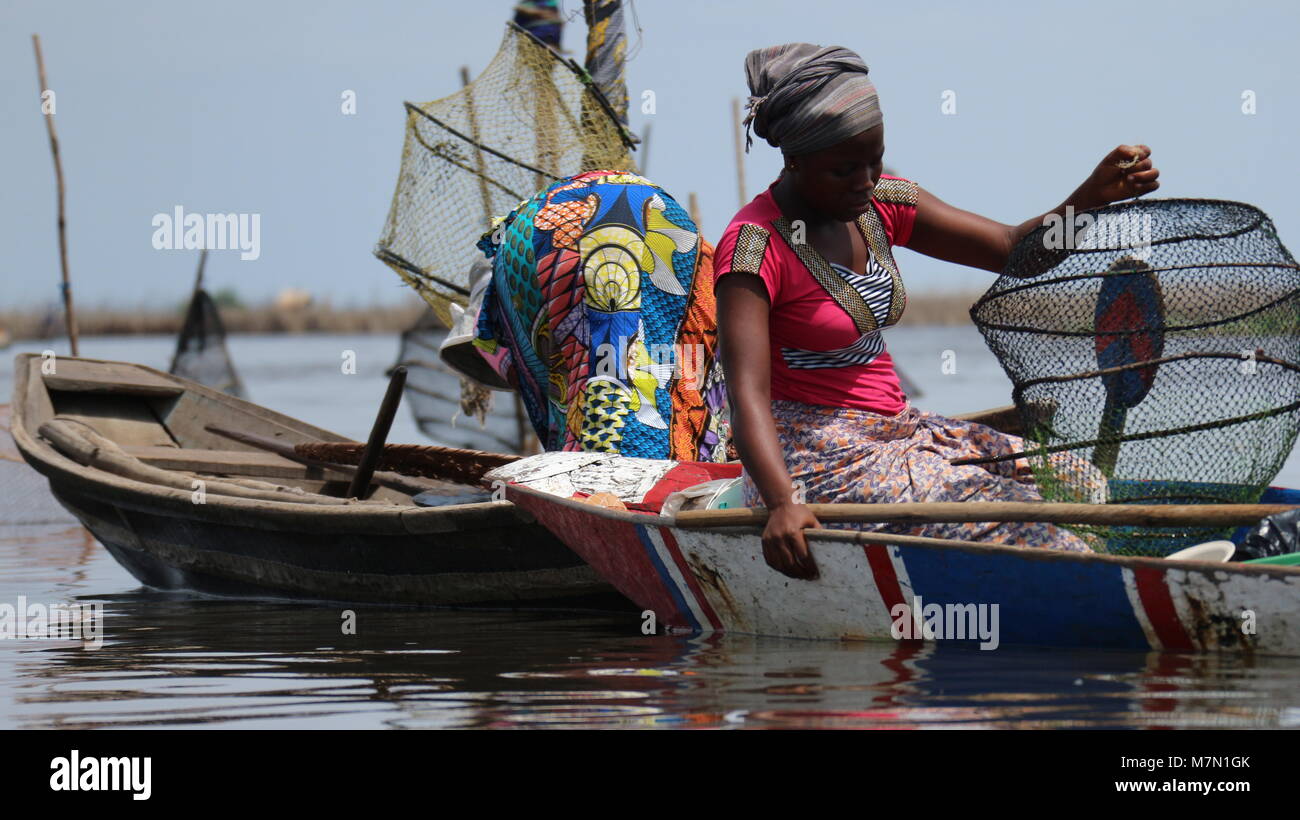 Two women in traditional clothes in boats holding fishing net baskets on  lake Nokoue, Ganvie village in Benin, West Africa,close up Stock Photo -  Alamy