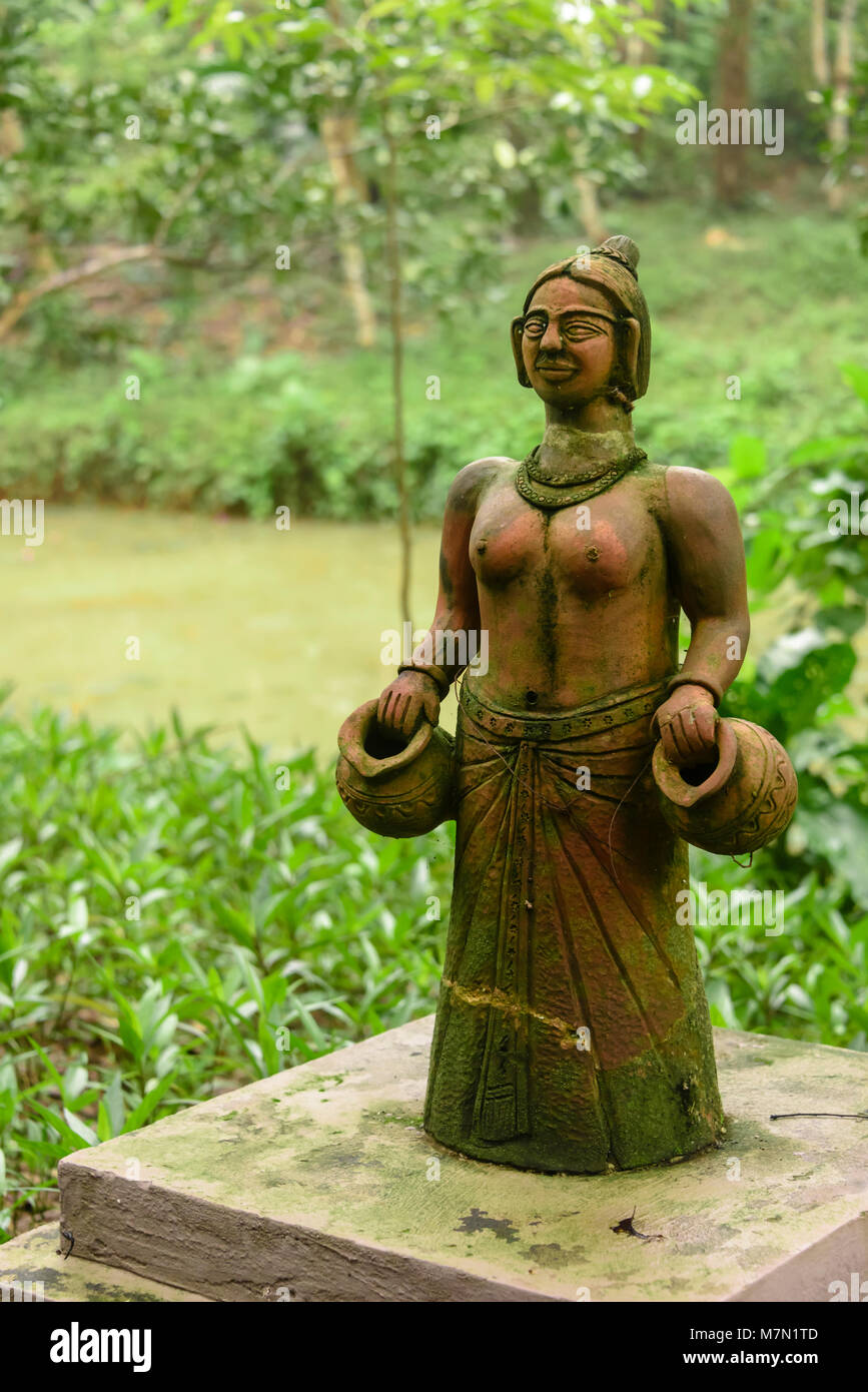 A terracotta stature of a native Vietnamese woman holding water jugs in the jungle garden of in the Pilgrimage Hotel, Hue, Vietnam Stock Photo