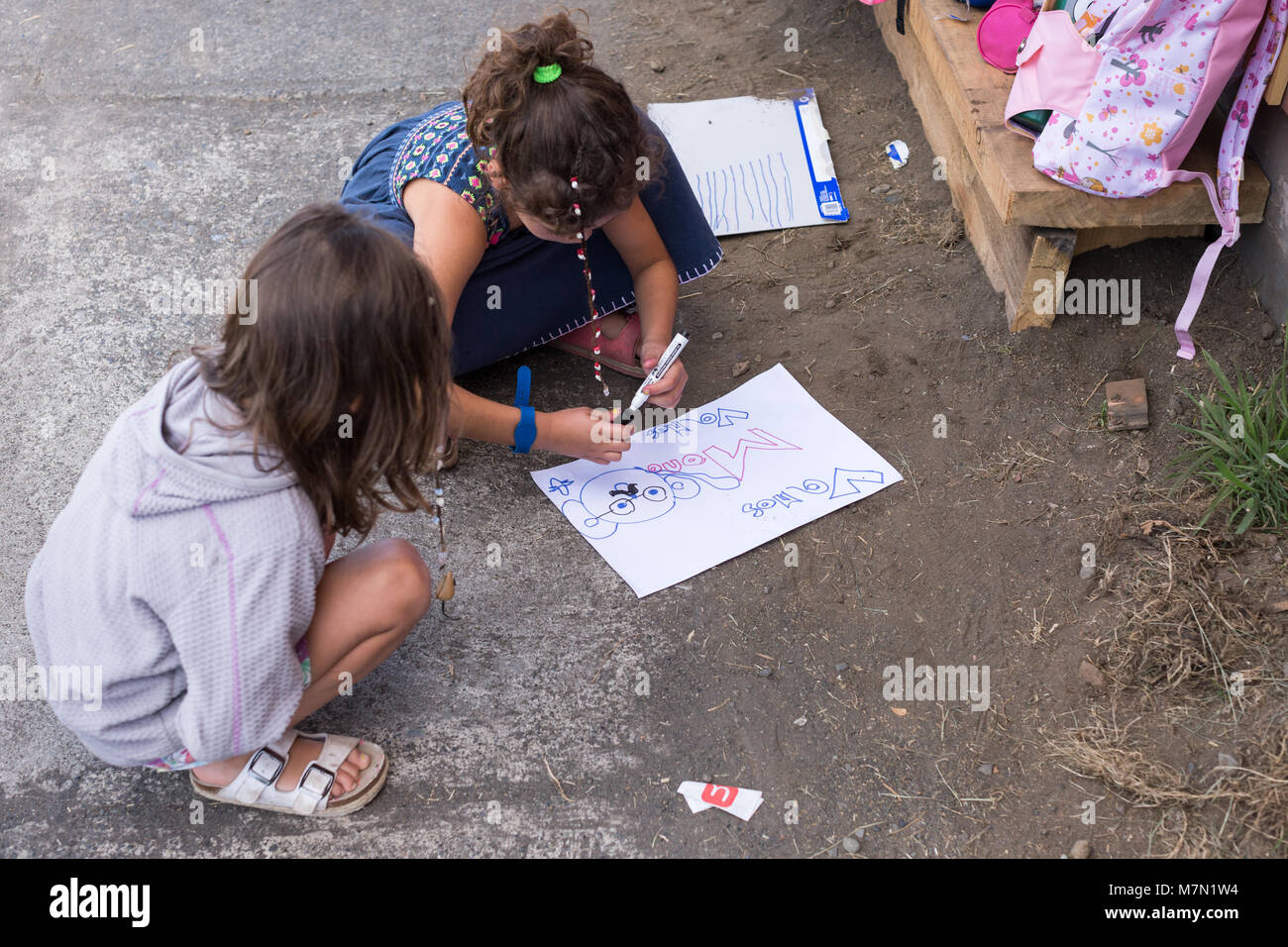 Little girls drawing a picture on the road in South America Stock Photo