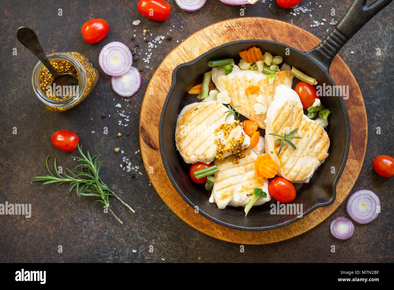 Grilled chicken fillet and various vegetables on a cast-iron frying pan. Copy space, top view flat lay background. Stock Photo