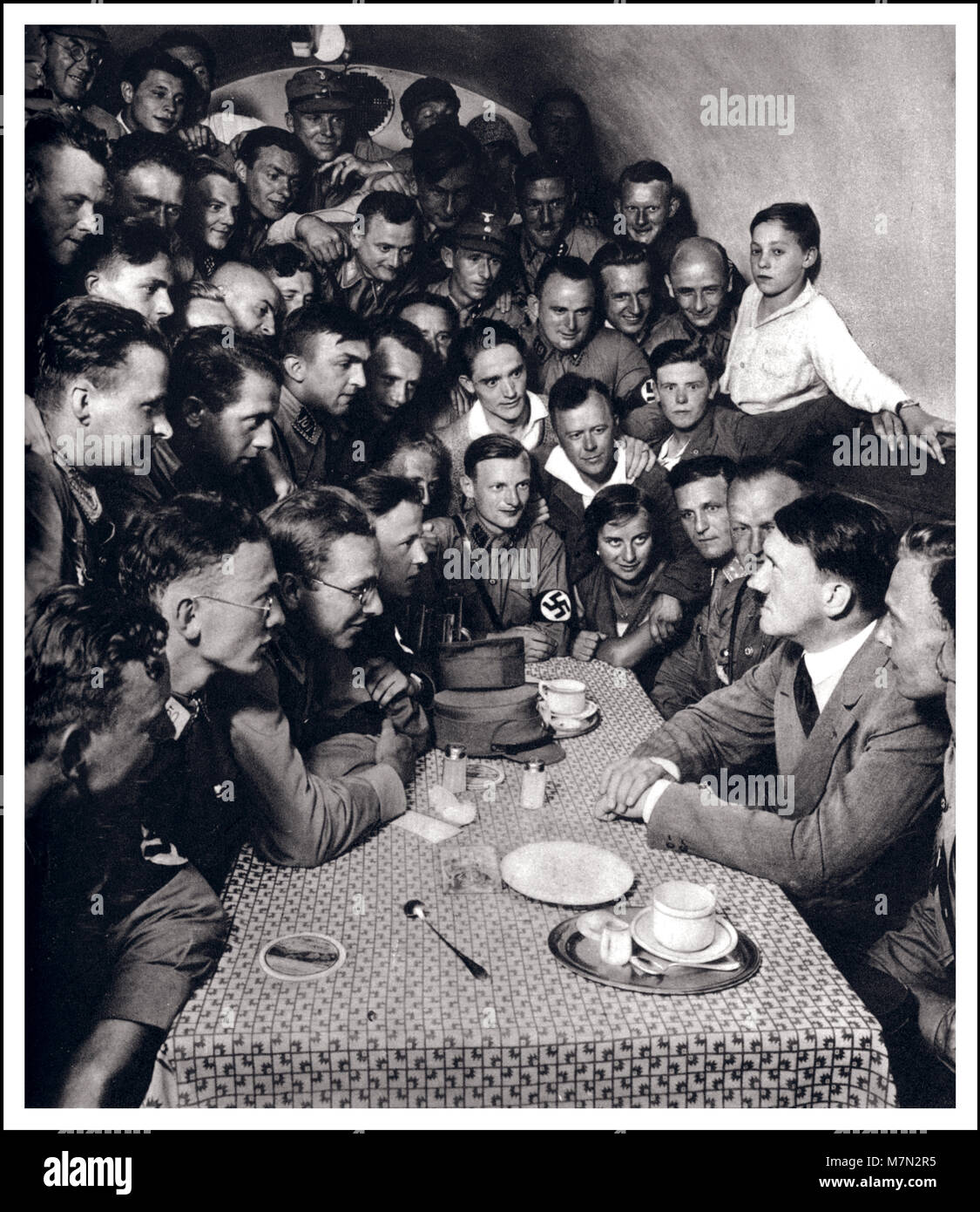 1933 Adolf Hitler posed propaganda image political meeting with SA men and other admirers in the basement casino of the Braunes Haus, headquarters of the National Socialist German Workers' Party ...Munich Germany (Deutschland erwacht - Werden Kampf und Sieg der NSDAP) Stock Photo