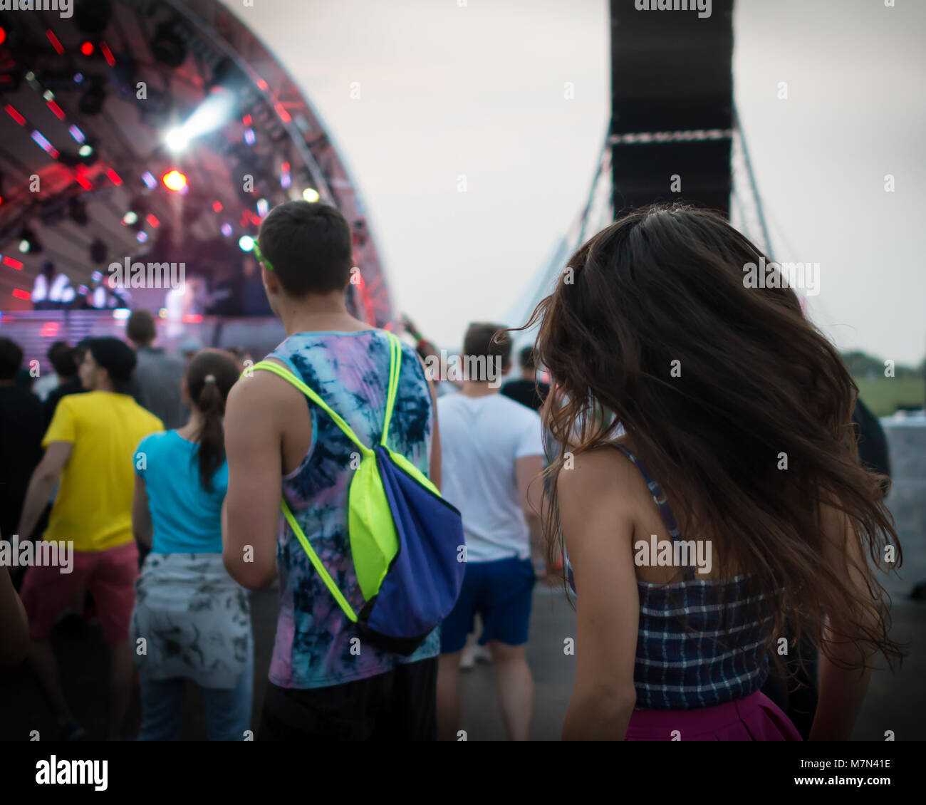 Back view of group of dancing people on the dance floor at music festival. Young trendy persons has fun outdoors Stock Photo