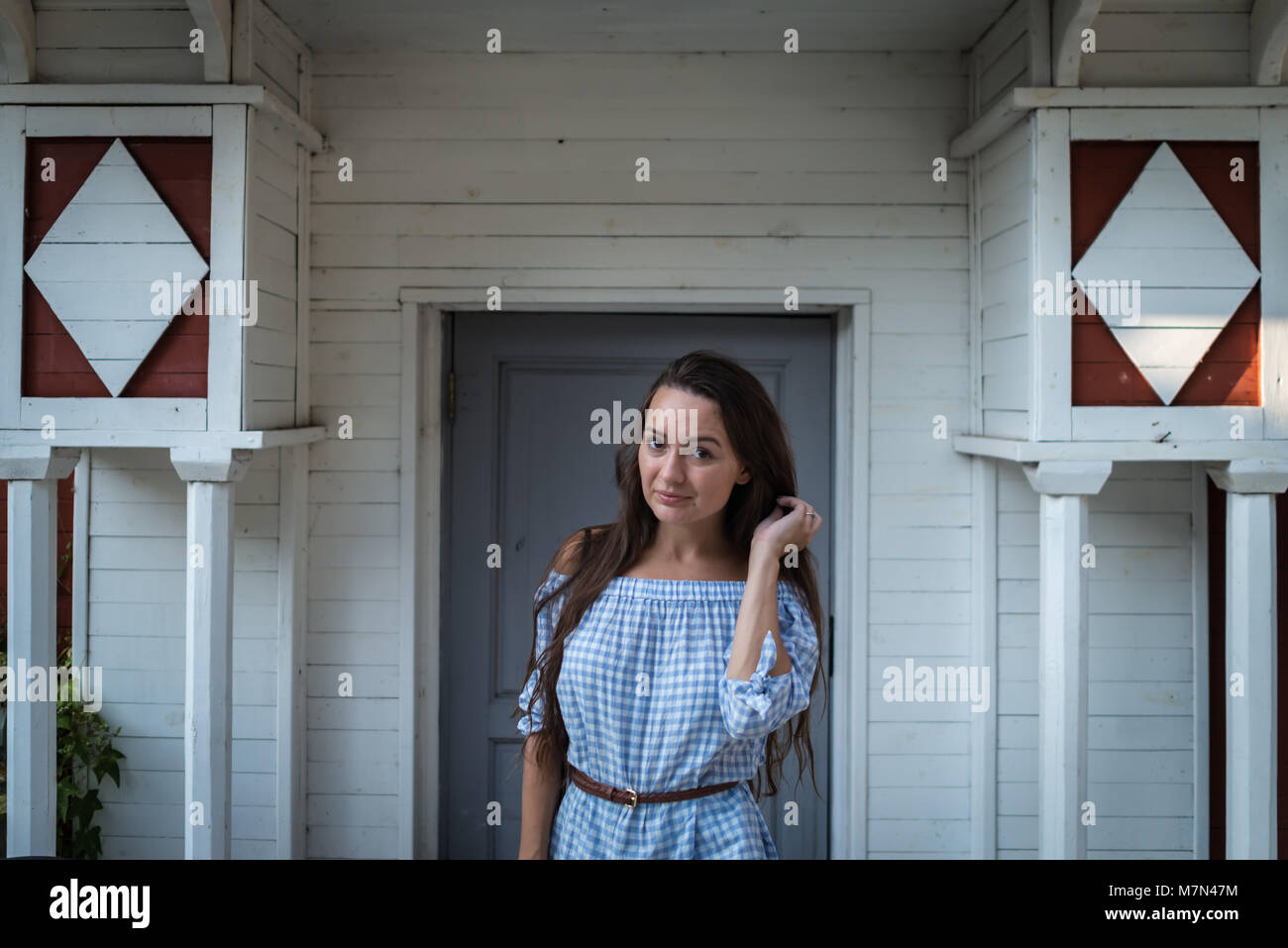 Young woman stands at the entrance of a colonial style wooden white ...