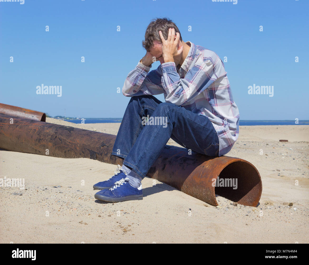 Lonely young man, suffering from depression sitting on wasteland Stock Photo