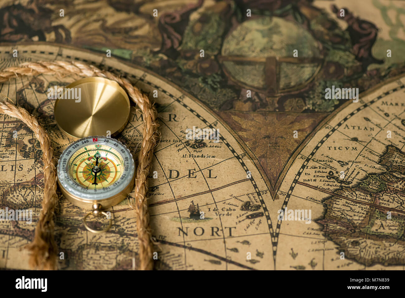Old compass on vintage map with rope closeup. Retro stale Stock Photo
