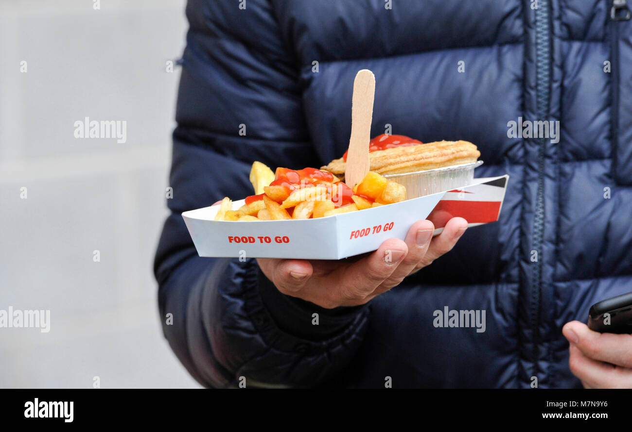 Football fan with Pie and chips with tomato sauce fast food takeaway food - Editorial use only. No merchandising. For Football images FA and Premier League restrictions apply inc. no internet/mobile usage without FAPL license - for details contact Football Dataco Stock Photo