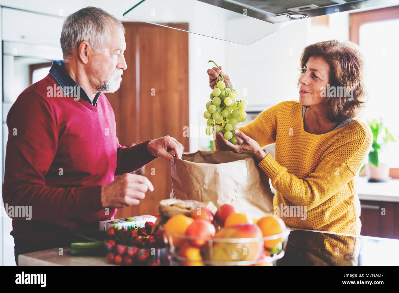 Senior couple unpacking fruit in the kitchen. Stock Photo