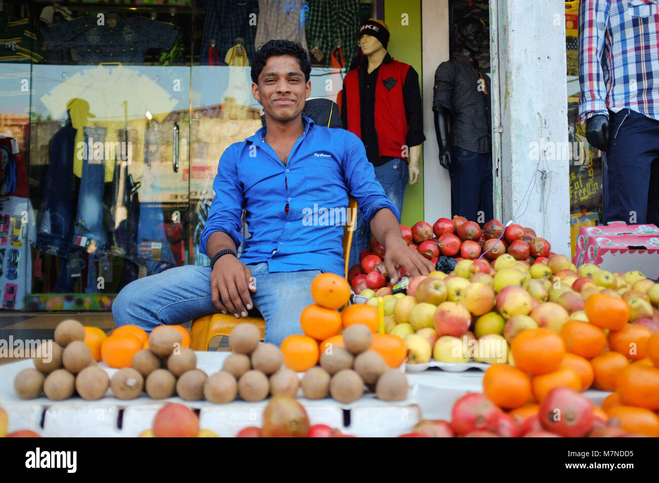 GOA, INDIA - JANUARY 27, 2015: Street fruit vendor sitting at fruit stand with a big smile. Stock Photo