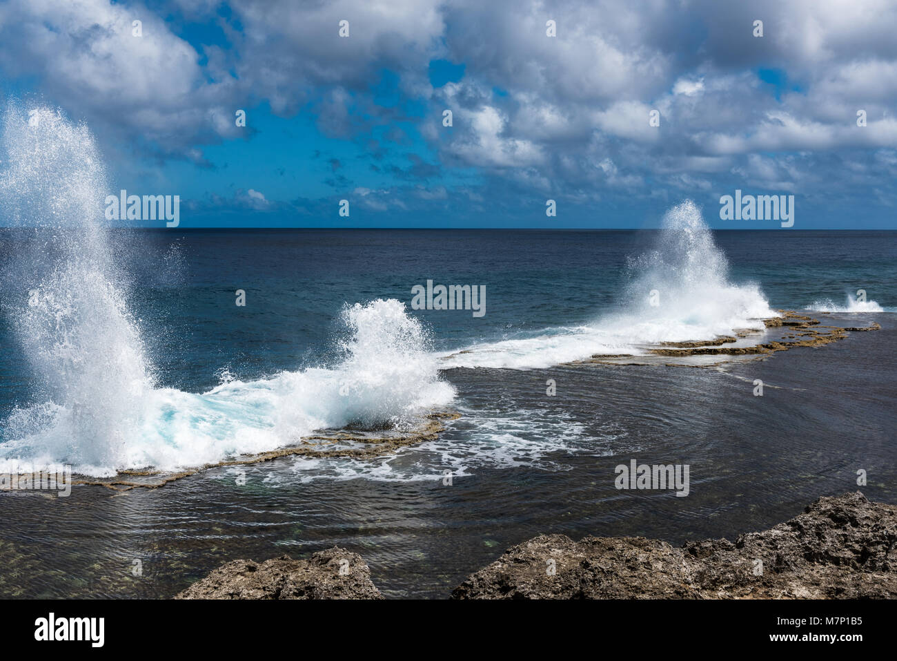Water shoots to the sky from blowholes on the coastline of Alofa as the tide rolls in Stock