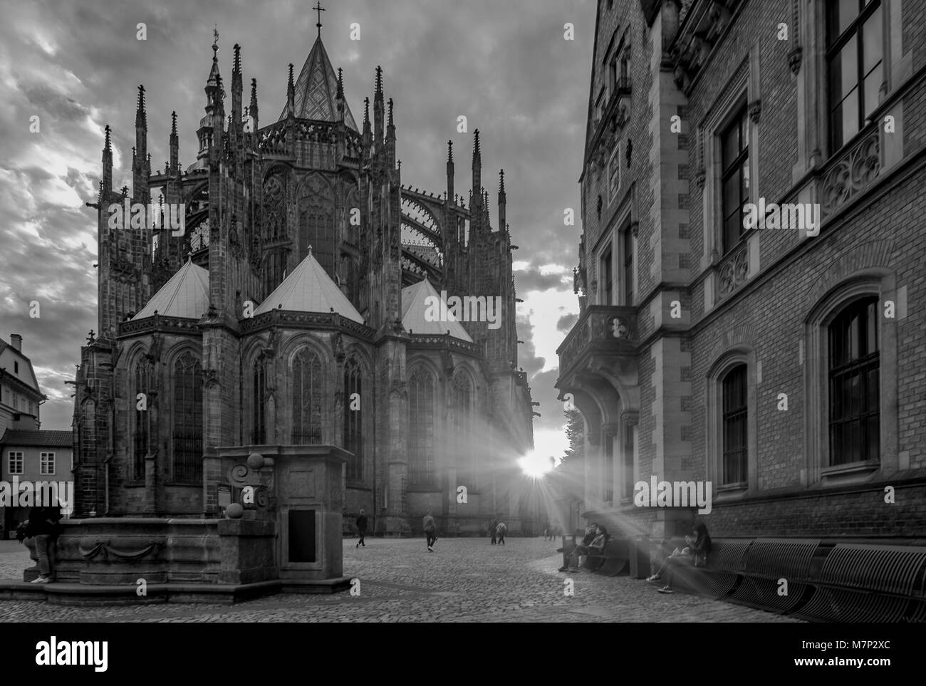 St. Vitus Cathedral in Prague Castle. The setting sun bursts from behind the cathedral in black and white Stock Photo