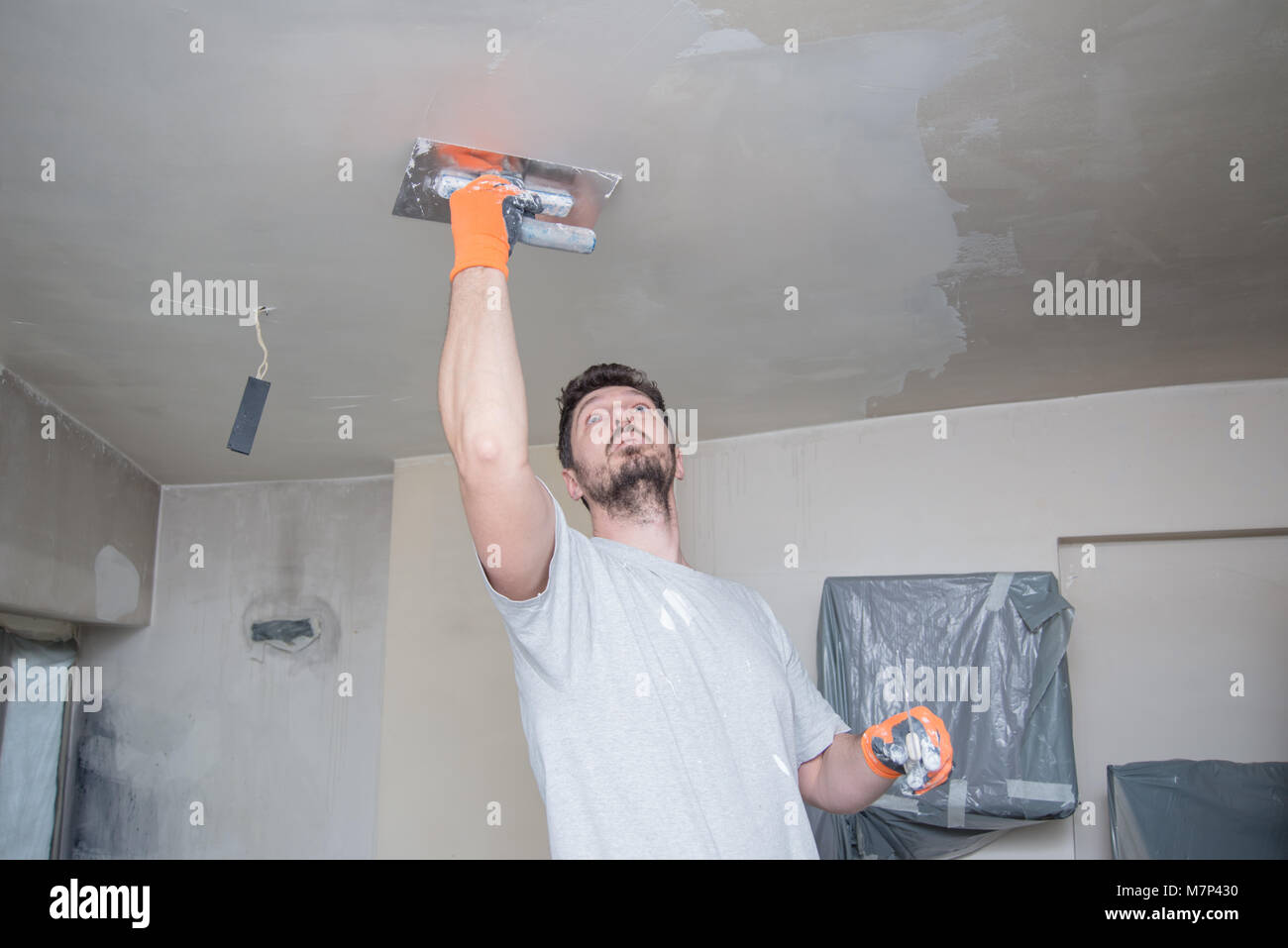 Worker Plastering Ceiling Stock Photo