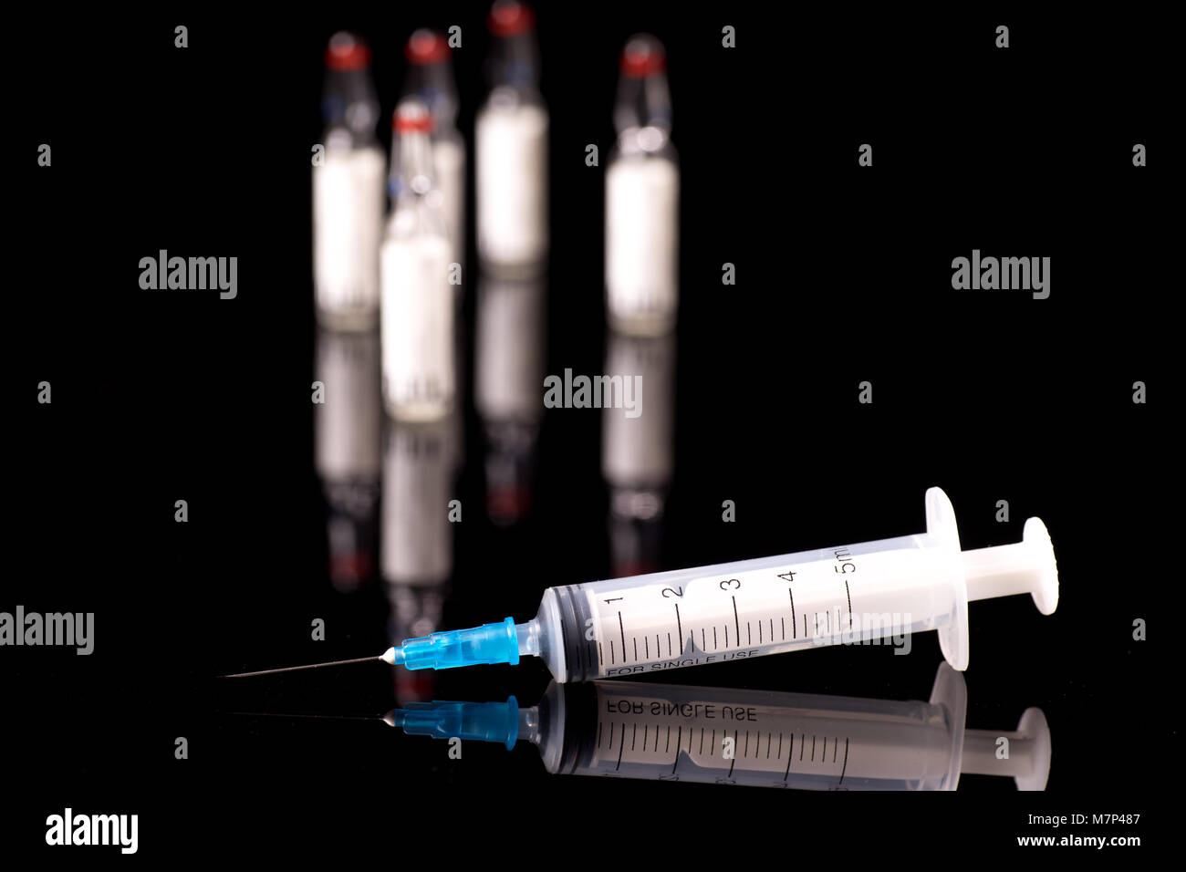 syringe and medical vials isolated on black blue background with glossy ...