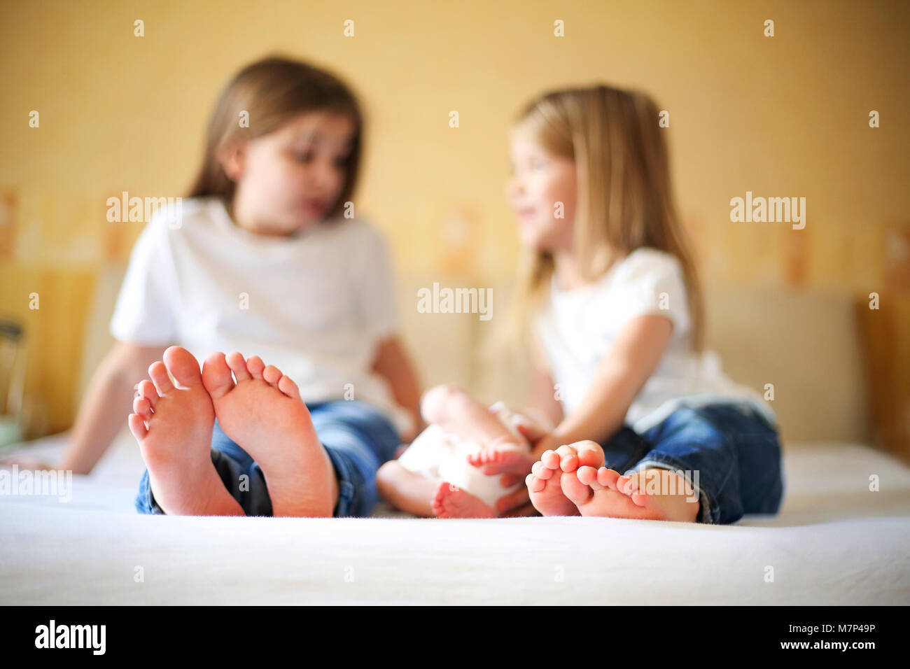 Sweet family in bed. Three sisters, close up on feet. Love and happiness concept Stock Photo