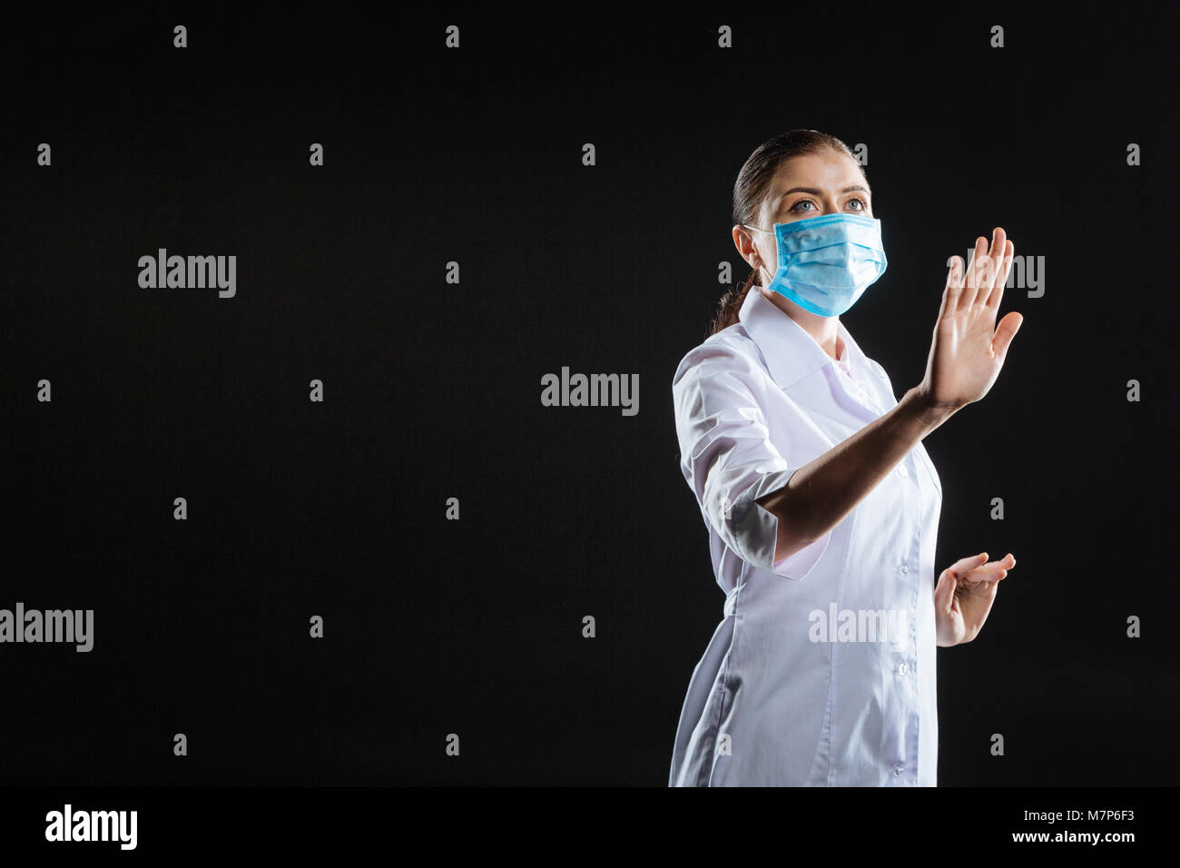 Busy concentrated medic lifting a hand and looking aside. Stock Photo