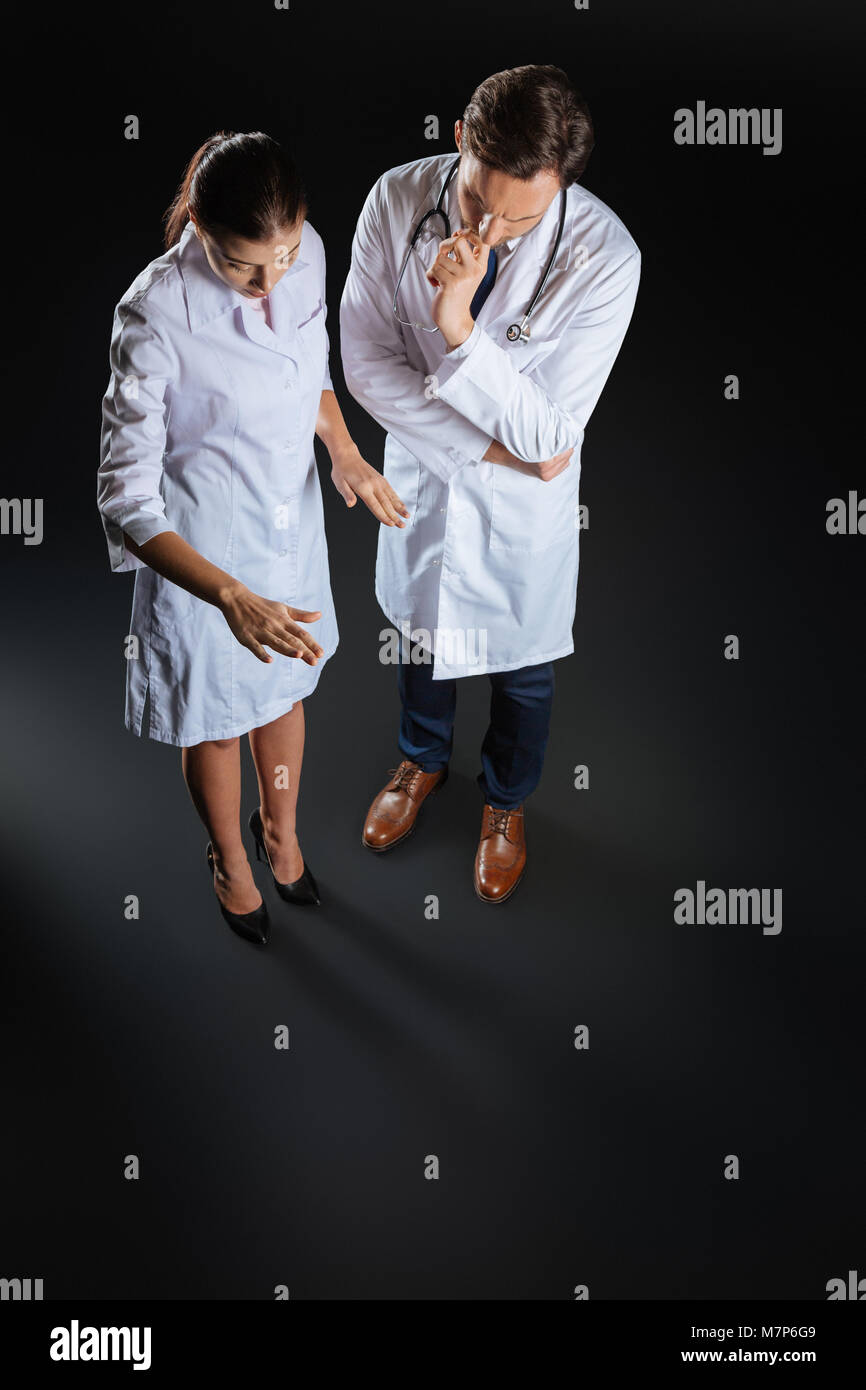 Busy pretty nurse standing and communicating with her colleague. Stock Photo