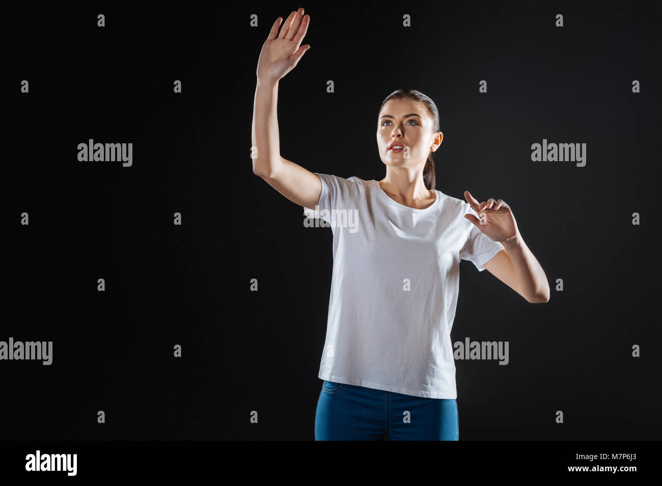 Creative pretty woman looking up lifting her hands. Stock Photo