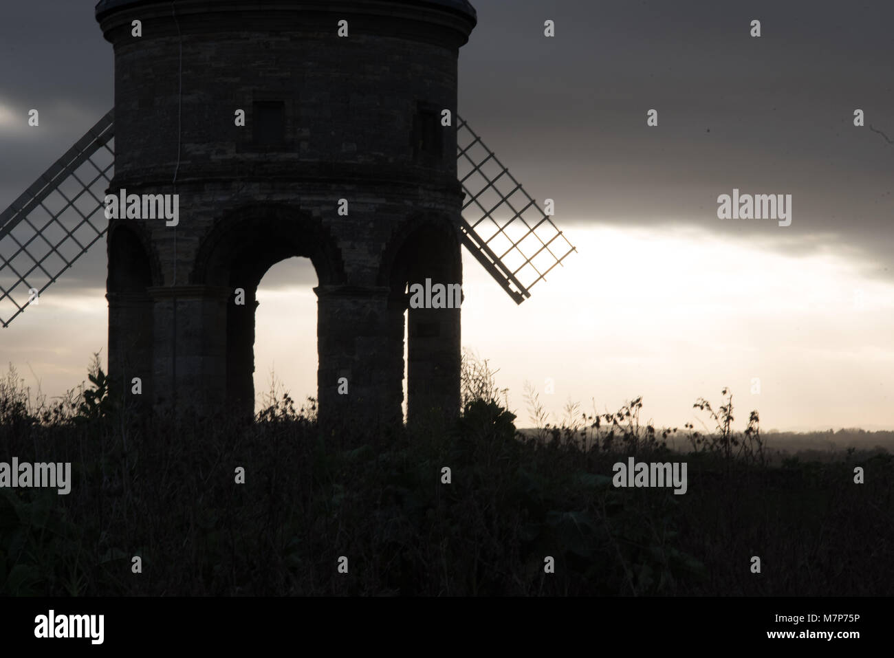 ealrly morning view through Chesterton windmill in Warwickshire UK with sun breaking through the sails Stock Photo