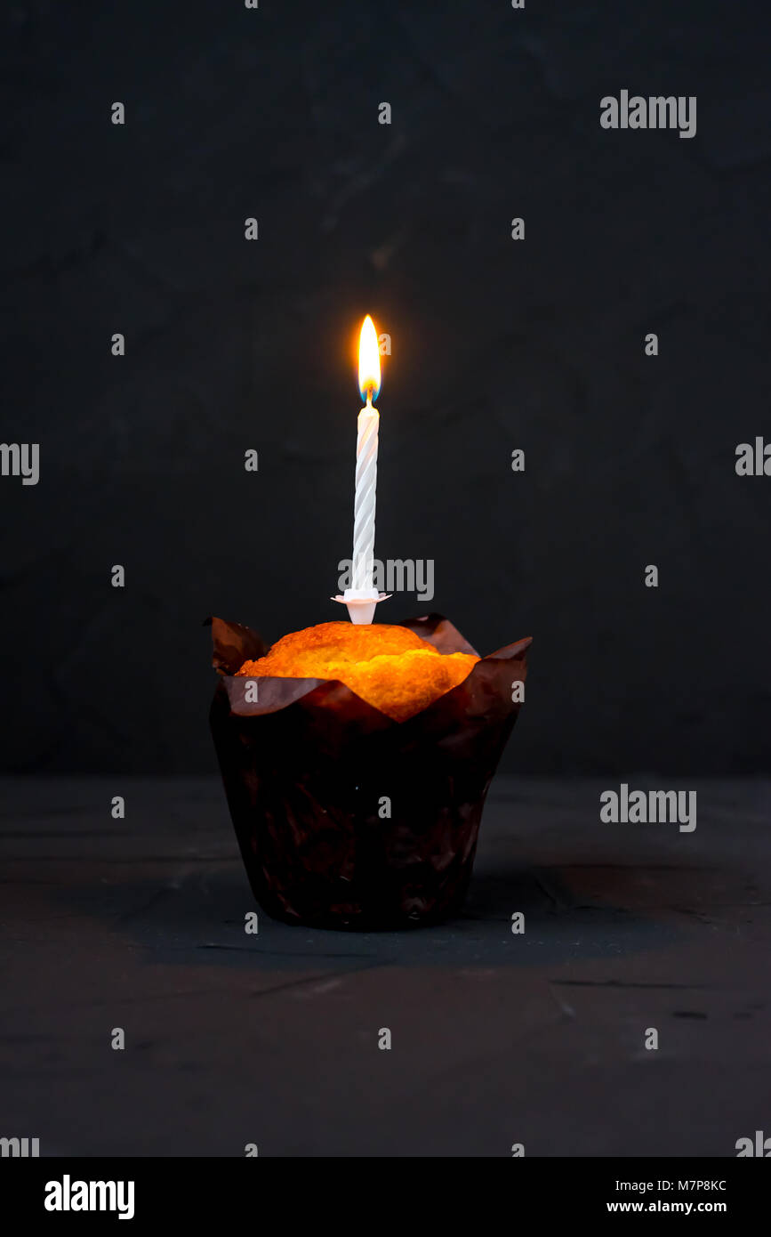 The candle burns on a cake on black background Stock Photo - Alamy