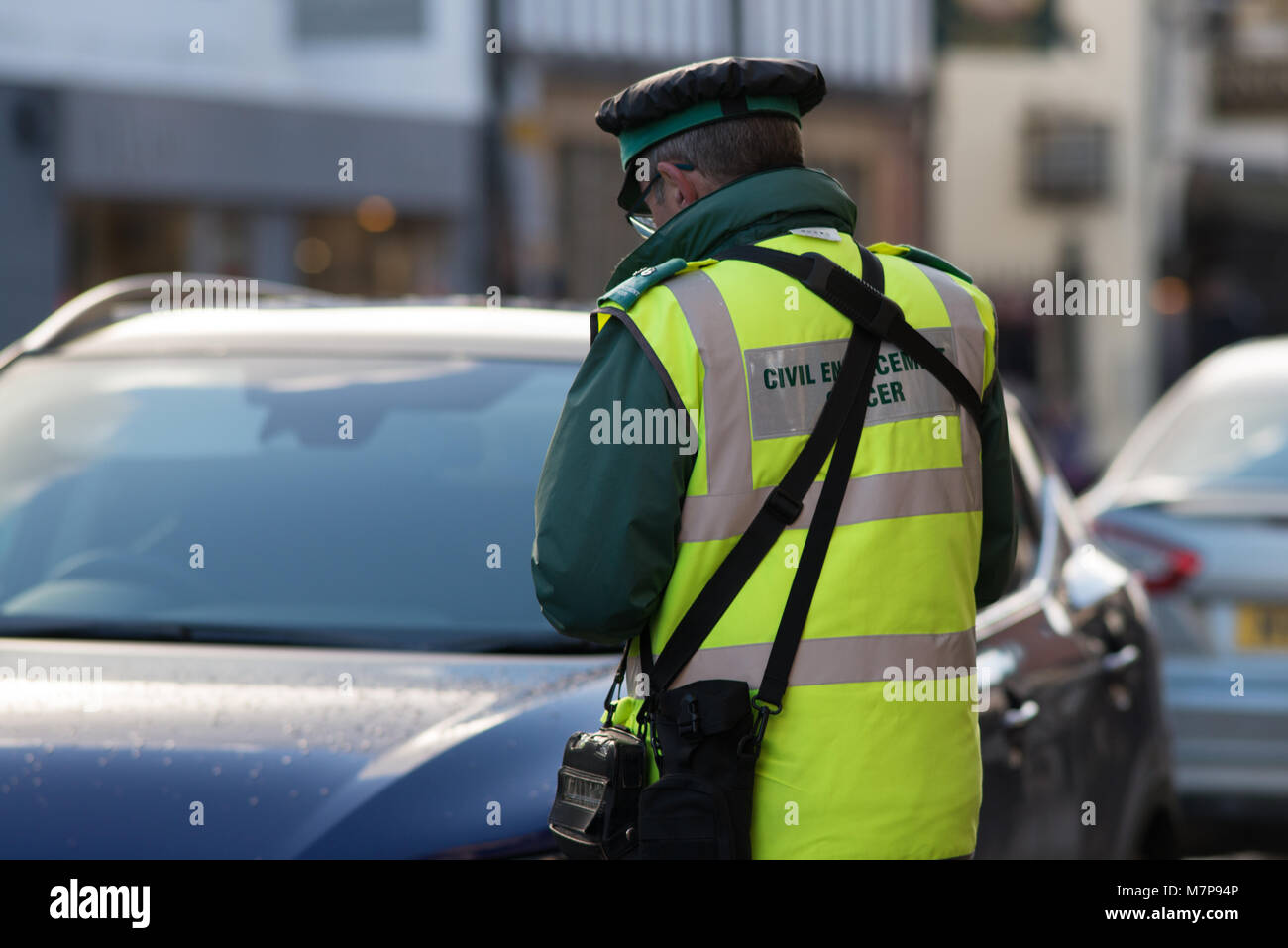 traffic warden civil enforcement officer issues parking ticket to illegally parked vehicle Stock Photo