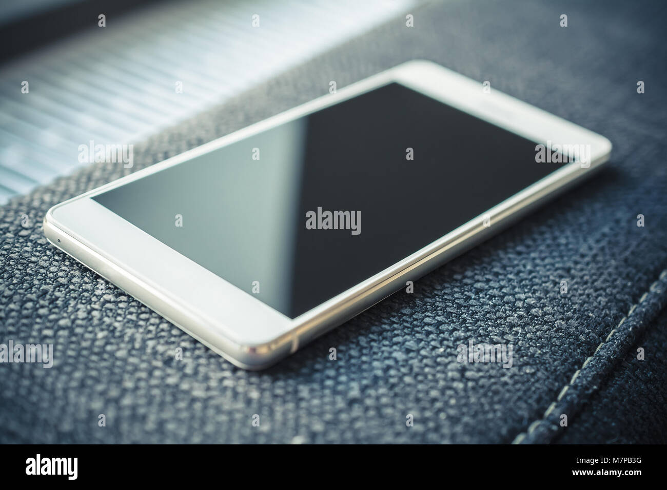 Smartphone With Reflection Lying On The Armrest Of A Couch Stock Photo
