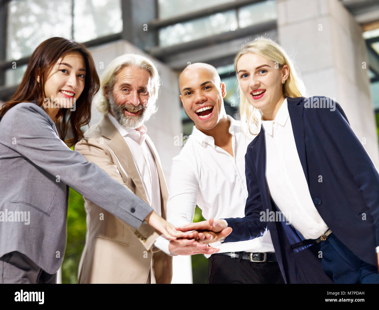caucasian asian latino corporate business people putting hands together showing unity and team spirit Stock Photo