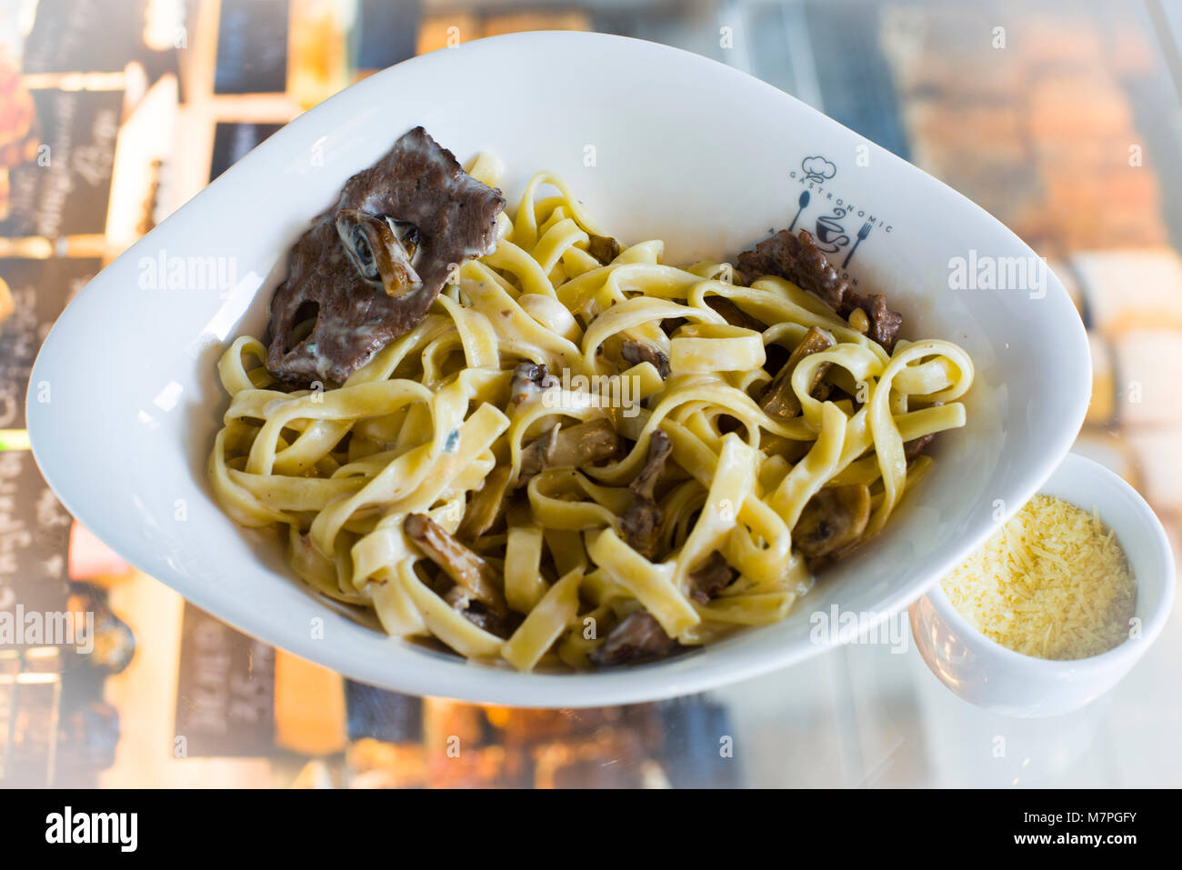 Pasta, prepared with cheese, green, meat, and served in oval deep porcelaine plate Stock Photo