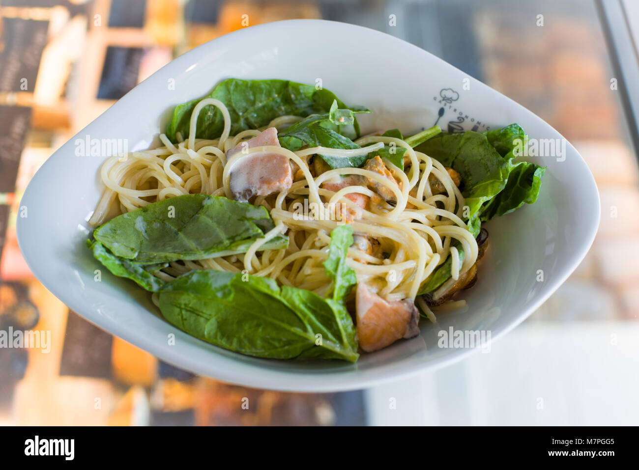 Pasta, prepared with cheese, green, meat, and served in oval deep porcelaine plate Stock Photo