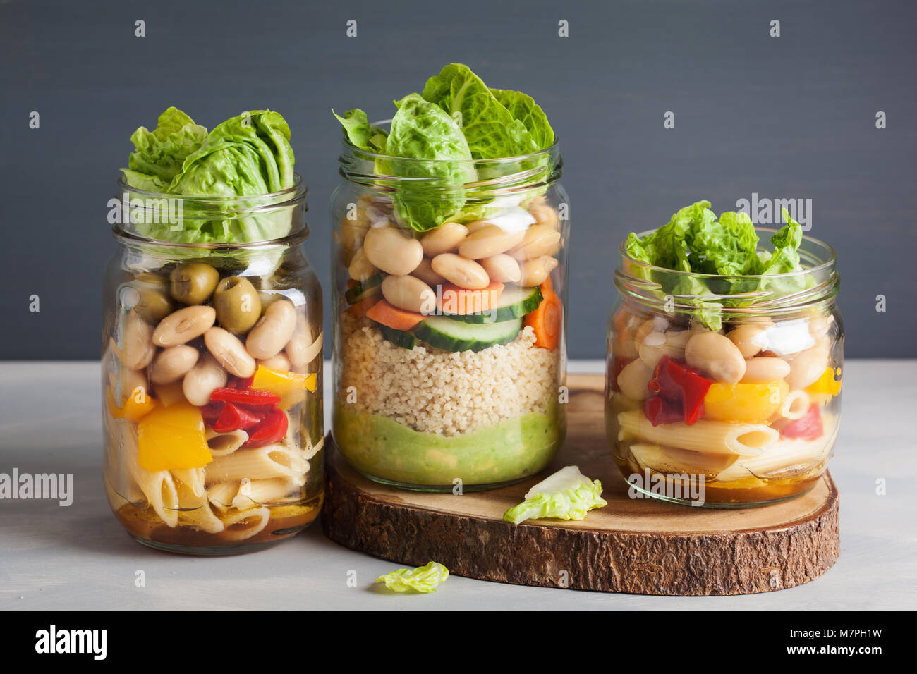 vegan couscous and pasta salad in mason jars with vegetables beans
