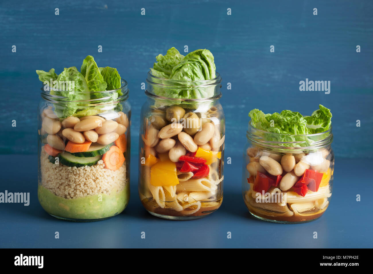 vegan couscous and pasta salad in mason jars with vegetables beans